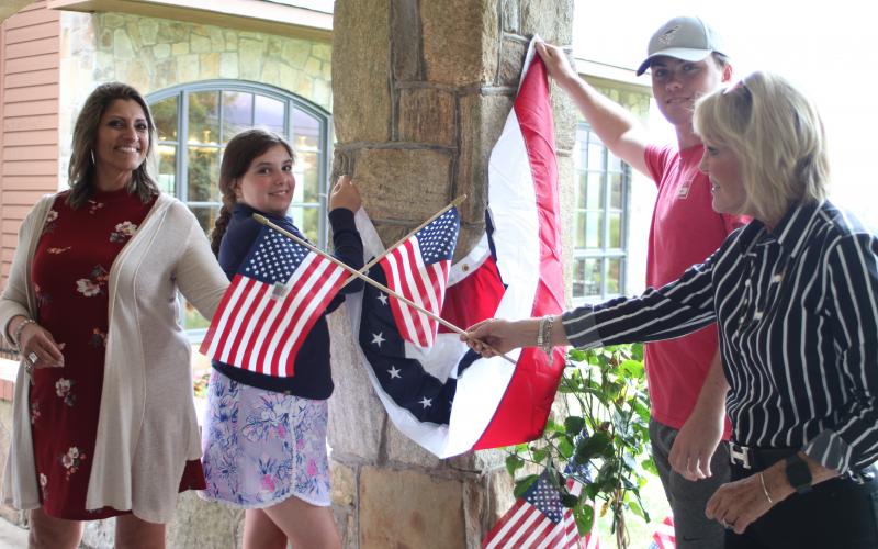 Megan Broome/The Clayton Tribune. Jo Flores, left, Blaire Cross, Dillard Cross and Louise Dillard, owner of The Dillard House, decorate The Rock House at the Dillard House in Dillard on Tuesday to prepare for upcoming Fourth of July festivities. The Dillard House will host a BBQ and live music on Saturday and Sunday. 