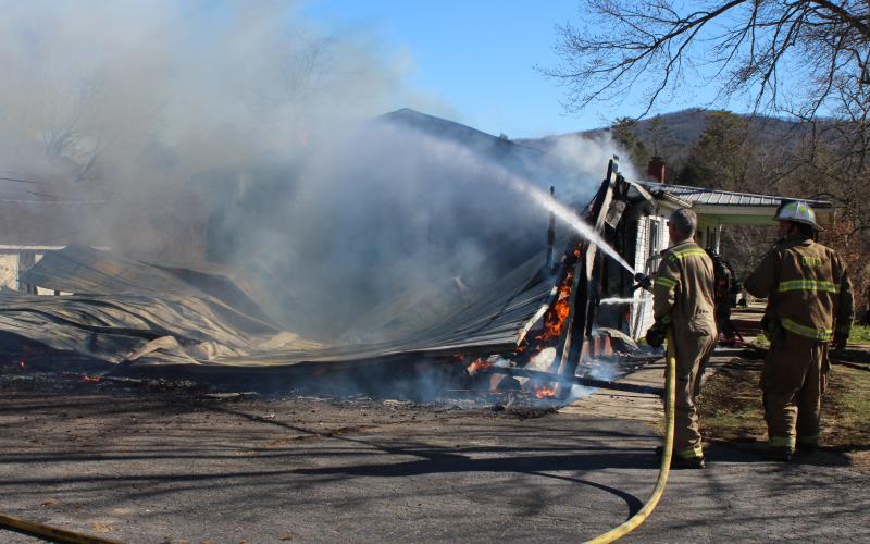 Megan Broome/The Clayton Tribune. Firefighters work to douse the remaining flames at a structure on Wolffork Church Road in Rabun Gap.