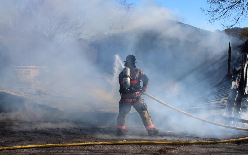 Megan Broome/The Clayton Tribune. Firefighters work to douse the remaining flames at a structure on Wolffork Church Road in Rabun Gap.